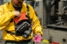 True North Gear Single Universal Radio Harness on Wildland Firefighter Putting Gear in Zipper Pocket